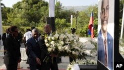 Haiti's Prime Minister Ariel Henry places flowers before a photo of slain Haitian President Jovenel Moise, during a ceremony in memory Moise two years after his killing, at the National Pantheon Museum in Port-au-Prince, Haiti, July 7, 2023.