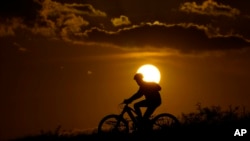 FILE - A cyclist tops a hill on a hot day at sunset, Aug. 20, 2023, in San Antonio. The U.N. weather agency said Earth sweltered through the hottest summer ever as record heat in August capped a brutal three months in the Northern Hemisphere.