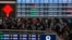 Travelers with luggage walk beneath a trains departure board as they arrive at the West Railway Station to catch their trains, in Beijing, Feb. 7, 2024. 