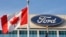 FILE - A Canadian flag flutters in the wind near a Ford logo on the automaker's headquarters, Oct. 26, 2009 in Dearborn, Mich. Canadian autoworkers ratified a new labor agreement with Ford Motor Co., Sept. 24, 2023, averting a threatened strike.