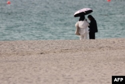 FILE - People take to the beach seeking respite from the heat in Dubai on July 7, 2023.