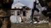 Quân nhân Ukraine đứng cạnh một tòa nhà bị phá hủy gần thị trấn tiền tuyến Kreminna, ngày 24 tháng 3 năm 2023.