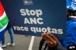A person holds a placard as supporters of the Democratic Alliance, South Africa's main opposition party, protest a proposal for employment quotas along racial lines, in Cape Town on July 26, 2023.