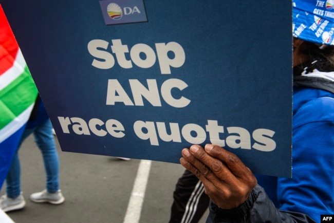 A person holds a placard as supporters of the Democratic Alliance, South Africa's main opposition party, protest a proposal for employment quotas along racial lines, in Cape Town on July 26, 2023.