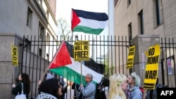 Demonstran pro-Palestina mengibarkan bendera Palestina di depan gerbang masuk Columbia University saat para aktivis pro-Palestina menggelar aksi perkemahan di dalam kampus tersebut di New York pada 22 April 2024. (Foto: AFP/Charly Triballeau)