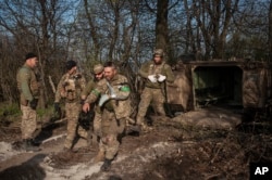 Vojni bolničari pomažu vojniku ranjenom u borbi da uđe u vozilo za evakuaciju kod Bahmuta, Donjecka oblast, Ukrajina, ponedeljak, 10. april 2023. (Foto: AP/Irina Ribakova)