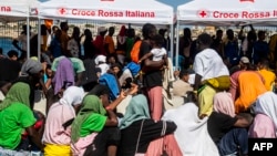 Migrants gather in the harbor of Italian island of Lampedusa before being transferred to Porto Empedocle in Sicily by the Italian military ship Cassiopea, Sept. 15, 2023.