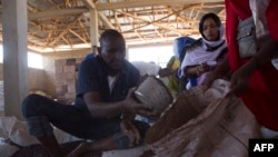 Mfanyakazi wa Shirika la Mpango wa Chakula Duniani (WFP) alisambaza chakula kwa wanawake wa Somalia Decemba19, 2017. Picha na Zacharias ABUBEKER / AFP