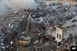 Palestinos inspeccionan los daños de los edificios destruidos tras los ataques aéreos israelíes en la ciudad de Gaza, el 25 de octubre de 2023.