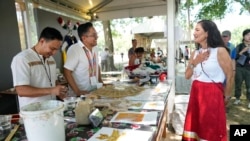 Interior Secretary Deb Haaland, right, visits a plaster art booth on opening day of the Smithsonian Folklife Festival on the National Mall in Washington, June 26, 2024.