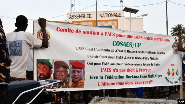 FILE - Supporters of the Alliance of Sahel States (AES) hold up a banner as they celebrate Mali, Burkina Faso and Niger leaving the Economic Community of West African States (ECOWAS), in Niamey, Niger, Jan. 28, 2024.