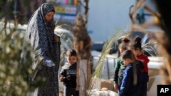 Palestinians visit the graves of people killed in the Israeli bombardment of the Gaza Strip and buried inside the Shifa Hospital grounds in Gaza City, Dec. 31, 2023.