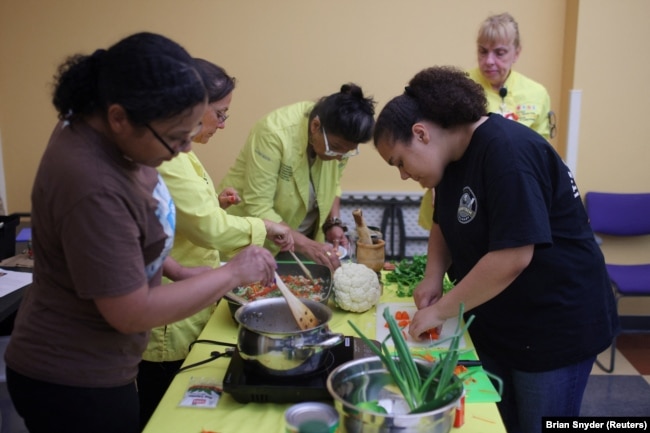 Jelainie and her mother make a vegetable dish with Holyoke Health Center staff, Massachusetts, June 11, 2024. (REUTERS Photo/Brian Snyder)