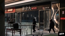 人們走過北京一處商業區關閉的餐廳。（2024年1月29日）