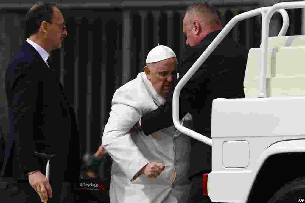 На папата Францис му се помага да влезе во папамобилот по неговата неделна аудиенција на плоштадот Свети Петар во Ватикан.