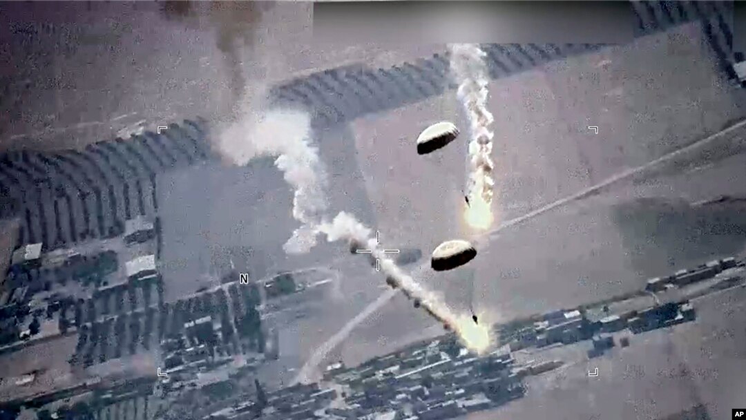 Foto dari tangkapan layar oleh Angkatan Udara AS tampak suar-suar yang dipasang di parasut melayang di udara. Suar-suar itu menurut AU AS dilepaskan oleh jet Rusia, SU-35, di atas wilayah udara Suriah, Rabu, 5 Juli 2023. (Foto: U.S. Air Force via AP)