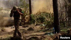 FILE - A Ukrainian serviceman with the 95th Brigade protects his ears from artillery noise, amid Russia's attack on Ukraine, at the front line in the region of Lyman, Ukraine, April 7, 2023.