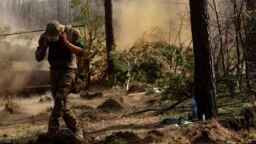 FILE - A Ukrainian serviceman with the 95th Brigade protects his ears from artillery noise, amid Russia's attack on Ukraine, at the front line in the region of Lyman, Ukraine, April 7, 2023.