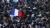 A demonstrator holds a French flag as people gather at the Place de la Republique after partial results in the second round of the early French parliamentary elections, in Paris, July 7, 2024.
