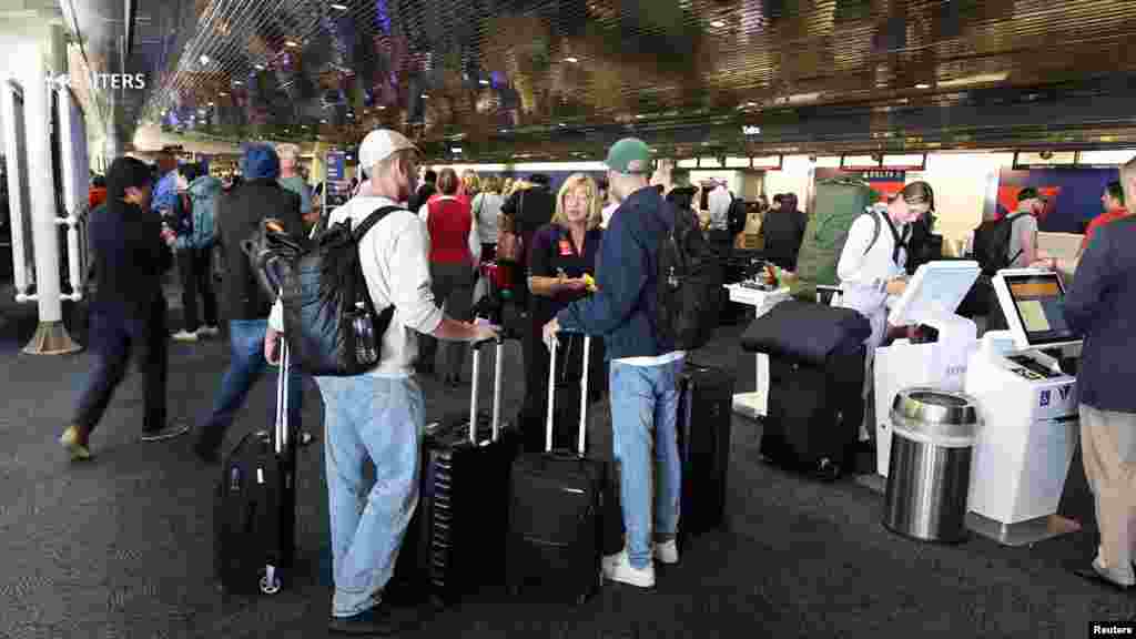 En el Aeropuerto Internacional de Newark, en Nueva Jersey, decenas de personas esperan con sus maletas debido a la suspensión de vuelos.