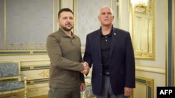 Ukrainian President Zelensky (L) and former US Vice President Mike Pence shake hands prior to their meeting. (Photo by Handout / AFP) 