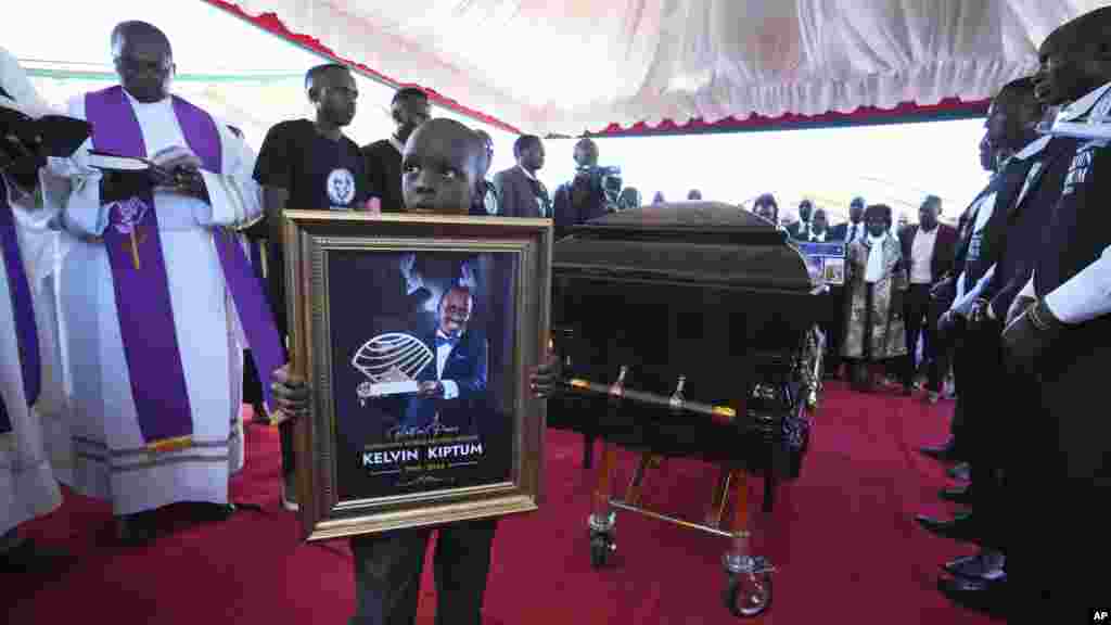 Caleb Kigen, son of marathon record holder Kelvin Kiptum, holds his late father&#39;s portrait ahead of his burial in Elgeyo Marakwet, Kenya. Kelvin Kiptum died in a road accident on Feb. 11, 2024.