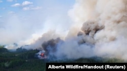 FILE — Smoke rises above the southeast perimeter of the Paskwa fire near Fox Lake, Alberta, Canada, May 16, 2023. Seventeen wildfires have broken out in Alberta in 2024; 52 have been burning since last year. (Alberta Wildfire/Handout via Reuters) 