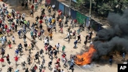Manifestantes correm em direcção à polícia de choque durante comício convocado por líder da oposição Raila Odinga devido ao elevado custo de vida, em Kibera, Nairobi 27 Março 2023

