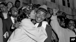 FILE - The Rev. Martin Luther King Jr. is welcomed with a kiss by his wife, Coretta, after leaving court in Montgomery, Alabama, March 22, 1956. (AP Photo/Gene Herrick)