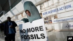 Alice McGown holds a sign while dressed as a dugong at the COP28 UN Climate Summit, Dec. 3, 2023, in Dubai, United Arab Emirates.