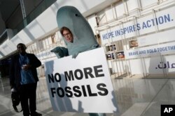 Alice McGown memegang tanda bertuliskan "tidak ada lagi fosil" sambil berpakaian seperti duyung di KTT Iklim PBB COP28, Minggu, 3 Desember 2023, di Dubai, Uni Emirat Arab. (Foto: AP)