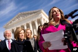 FILE - Lorie Smith, a Christian graphic artist and website designer in Colorado, right, accompanied by her lawyer, Kristen Waggoner of the Alliance Defending Freedom, second from left, speaks outside the Supreme Court in Washington, Dec. 5, 2022.