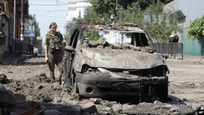 An investigator looks at a destroyed car after the shelling that Russian officials in Donetsk said was conducted by Ukrainian forces, in Donetsk, Russian-controlled Donetsk region, eastern Ukraine, July 31, 2023.