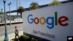 FILE - A man walks past a Google sign in San Francisco, May 1, 2019.