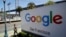 FILE - A man walks past a Google sign in San Francisco, May 1, 2019.