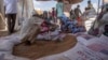 FILE - Refugees collect food rations at a USAID distribution point in eastern Sudan, March 24, 2021. With violence flaring in the country again, USAID is deploying a team of disaster response experts to coordinate a humanitarian strategy.