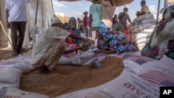 FILE - Refugees collect food rations at a USAID distribution point in eastern Sudan, March 24, 2021. With violence flaring in the country again, USAID is deploying a team of disaster response experts to coordinate a humanitarian strategy.