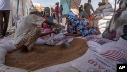 FILE - Refugees collect food rations from USAID at a distribution point in Sudan, March 24, 2021. With violence flaring in the country again, USAID is deploying a team of disaster response experts to coordinate a humanitarian response.