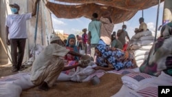 ARCHIVO - Refugiados recogen raciones de alimentos de la Agencia de Estados Unidos para el Desarrollo Internacional (USAID) en un punto de distribución en el este de Sudán, el 24 de marzo de 2021. Los recortes presupuestarios de Estados Unidos creearían déficit para la agencia.