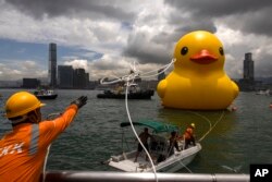 Sebuah instalasi seni yang disebut "Double Ducks" oleh seniman Belanda Florentijn Hofman dipamerkan di Pelabuhan Victoria di Hong Kong, Jumat, 9 Juni 2023. (AP/Louise Delmotte)