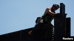 ARCHIVO - Un trabajador instala vigas de acero en un edificio en construcción durante una ola de calor de verano en Boston, el 30 de junio de 2021.