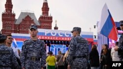 FILE - Russian National Guard (Rosgvardiya) servicemen keep watch as people gather for a concert dedicated to the first anniversary of the annexation of four regions of Ukraine Russian troops control, at Red Square in central Moscow, Sept. 29, 2023.