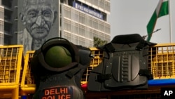 FILE - A picture of Mahatma Gandhi is displayed on a government building as riot gear lies on a barricade put up by police during a political protest in New Delhi, India, March 22, 2024. 