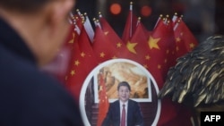 FILE - A man looks at a decorative plate featuring an image of Chinese President Xi Jinping at a souvenir store next to Tiananmen Square in Beijing on Feb. 27, 2018.