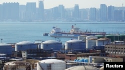 FILE - A China Ocean Shipping Company (COSCO) vessel is seen near oil tanks at the China National Petroleum Corporation (CNPC)'s Dalian Petrochemical Corp in Dalian, Liaoning province, China, October 15, 2019.