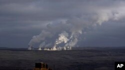 FILE - Steam rises from a power plant located by the Turow lignite coal mine near the town of Bogatynia, Poland, Jan. 15, 2022.