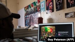 A man explains how he creates protest scenes using an AI prompt website that then can be used for posters and social media posts at his shop in Dakar on February 13, 2024.