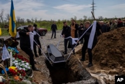 Undertakers lower the coffin of Ukrainian serviceman Andrii Romanenko at the Kryvyi Rih cemetery in eastern Ukraine, April 24, 2023.