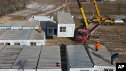 In this photo released by Xinhua News Agency, movable plank houses for earthquake victims are set up in Meipo Village, Jishishan County in northwest China's Gansu Province, Dec. 21, 2023. 