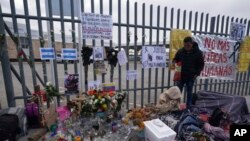 Un altar con velas y fotos cubre la cerca afuera del centro de detención de migrantes que fue el sitio de un incendio mortal, mientras los migrantes se despiertan después de pasar la noche en la acera en Ciudad Juárez, México, el jueves 30 de marzo de 2023.